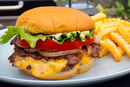 A crispy-edged burger with lettuce, tomato, onions, cheese, and mayo on a soft bun—made using the Braize Smash Burger Press with Folding Handle & 50 Non-Stick Paper Sheets—served with crinkle-cut fries on a gray plate.