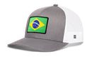 Haka Hat Brazil Flag International Trucker Hat by Haka Hat is a gray and white Brazilian snapback featuring a patch of the Brazil flag on the front panel. This trucker hat has a structured crown, curved brim, and mesh back for ventilation.