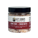 A clear plastic jar of B.T. Leigh’s Aleppo & Garlic Finishing Salt with a black lid and a white label, containing savory garlic seasoning and kosher salt flakes.