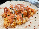 A flour tortilla topped with scrambled eggs, shredded cheese, herbs, and a generous drizzle of Terrapin Ridge Farms Everything Aioli Garnishing Squeeze, ready to be wrapped into a delicious breakfast burrito.