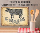 Butcher's cut diagram on a metal sign with wooden utensils in a container below.