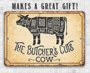 Vintage-style sign with cow cut diagram and text 'The Butcher's Cuts Cow' on a tiled wall background.