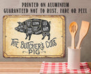 Butcher's cuts diagram on a vintage-style metal sign with wooden utensils in the foreground.
