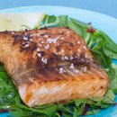 Grilled salmon fillet topped with The Spice Lab Fleur de Sel Sea Salt, served on a bed of fresh mixed greens with a lemon wedge on a blue plate.