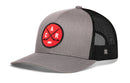 Introducing the Haka Hat Carolina Hockey Trucker Hat | Red CAR X Snapback: A gray and black signature trucker hat from Haka Hat, featuring a bold red circular patch with crossed hockey sticks and the letters C, A, and R—paying tribute to Raleigh, North Carolina’s devoted fans. The solid gray front pairs with breathable black mesh sides and back for a look that’s both stylish and comfortable.