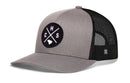 The Haka Hat Charleston Trucker Hat | CHS X Snapback features a gray and black design with a round front patch displaying “CHS” and a small shape, plus mesh material on the back and sides.