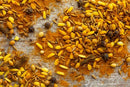 A close-up of mixed Indian spices—such as turmeric, cumin seeds, fennel seeds, coriander seeds, and whole cloves—essential ingredients in World Spice Poudre de Colombo Curry by World Spice—scattered on a textured surface.