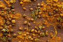 A close-up of various whole and ground spices, including coriander seeds, dried herbs, and a hint of World Spice Turkish Curry by World Spice scattered across a wooden surface creates the perfect foundation for an aromatic spice blend.