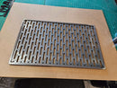 The DDR Fab Custom Grill Grate (29.5" x 18.5" x 1/2") with evenly spaced slots rests on cardboard atop a green cutting mat.