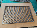 A DDR Fab Custom Grill Grate (28" x 21" x 1/2") with a diamond-pattern lattice rests on cardboard, while a green cutting mat and an additional metal grate are partly visible in the background.