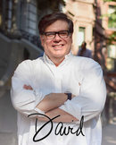 A man in a white shirt stands outdoors with his arms crossed, smiling proudly beside his homemade corned beef made using the World Spice Corned Beef Cure & Cook Kit from World Spice. Sunlight highlights his face, and the name “David” appears in script at the bottom of the image.