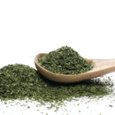 A wooden spoon holds a generous heap of The Spice Lab Fancy Chervil, a delicate dried green herb by The Spice Lab that’s perfect for French cooking and fines herbes blends, with more chervil scattered on a white background.