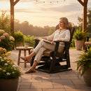 A woman relaxes in the Kanyon Living Adirondack Poly Glider Swivel Chair Deluxe in Antique Mahogany and Black, enjoying a book among potted plants, string lights, and stylish outdoor decor as the sun sets.