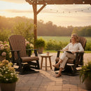 A woman relaxes at sunset on the Kanyon Living Adirondack Poly Glider Swivel Chair Deluxe in Antique Mahogany and Black, surrounded by potted flowers, enjoying a drink at a small table under a pergola.