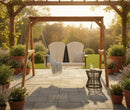 The Kanyon Living Poly Lumber 4′ Adirondack Swing in Seashell and Black hangs beneath a pergola on a stone patio with potted plants, cozy cushions and blankets, creating a peaceful spot alongside stylish outdoor porch furniture.