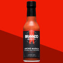DDR BBQ Supply Bravado Spice Ancho Masala Scorpion-Reaper hot sauce bottle against a vibrant red background.