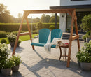 The Kanyon Living Poly Lumber 4′ Adirondack Swing in Aruba Blue & White sits on a stone patio with potted flowers and a small table of sliced fruit, complementing the modern house, green lawn, and offering eco-friendly comfort outdoors.