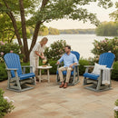 A woman pours a drink for a seated man on a patio featuring Kanyon Living Adirondack Poly Glider Swivel Chairs in blue & light grey, with a small round table and lush greenery overlooking a calm lake.