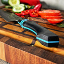 DDR BBQ Supply Spaceman Knives Calypso Kiritsuke with a black G10 handle and blue accents on a wooden cutting board.