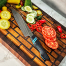 DDR BBQ Supply Spaceman Knives Calypso Kiritsuke with VG10 steel blade and black G10 handle on a wooden cutting board