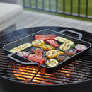 The Napoleon Cast Iron Griddle Pan for Griddles (56084) by Napoleon Grills, filled with sliced zucchini, bell peppers, mushrooms, and onion, sits on a charcoal grill with seared veggies and rising smoke—an ideal grill accessory.