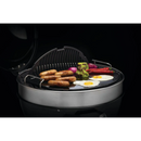 DDR BBQ Supply porcelain-enameled cast iron reversible griddle on a 22-inch charcoal grill cooking sausages and eggs.