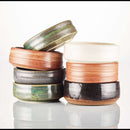 DDR BBQ Supply handmade ceramic shave bowls in assorted earthy glazes stacked on a white reflective surface.