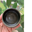 DDR BBQ Supply handmade dark ceramic shaving bowl with a slip-resistant design for soap pucks held in a hand.