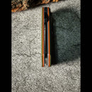 DDR BBQ Supply Galatea folding pocket knife showing the G10 handle spine with orange and olive green layered detail