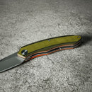DDR BBQ Supply Spaceman Knives Galatea folding pocket knife with olive green G10 handle on a textured grey surface