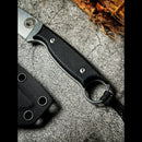 A close-up of the Spaceman Knives Halimede Fixed Blade Knife, featuring a black Micarta handle with finger ring and lanyard, lies on a textured gray surface next to its black sheath and coiled rope.