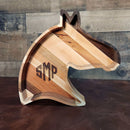 The Two Acre Woodworks Wooden Horse Head Serving Tray With Custom Engraving Options features light and dark wood stripes, a personalized engraving, and is shown on a brown surface with a rustic wooden background.