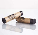 DDR BBQ Supply Super Manly Tough Guy lip balm tubes with kraft paper labels and black caps on a reflective surface