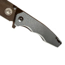 Close-up of the Spaceman Knives Naiad EDC Pocket Knife, featuring a textured black handle and partially visible titanium-plated blade, photographed on a white background.