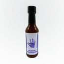 A bottle of Culture Hot Sauce Persian Persuasion from Culture Hot Sauce, showcasing a striking purple hand and knife graphic on a white label. This distinctive Persian hot sauce is made with fragrant spices and tangy dried lime (Limu Omani), offering bold flavor in every drop.