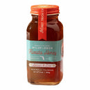 A 9 oz glass jar of Honey Truck Co Raw Florida Wildflower Honey, featuring a red lid and a turquoise and red label with the words “Artisan & Raw, Minimally Filtered”—an ideal pick for anyone looking for local, raw, and unfiltered Florida honey.