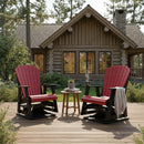 Two Kanyon Living Adirondack Poly Glider Swivel Chairs in red and black sit on a deck outside a log cabin, providing cozy outdoor seating with a mug, book, blanket, and lush greenery enhancing the relaxing atmosphere.