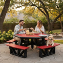 A man and woman enjoy a meal at a Kanyon Living Poly Picnic Table Octagonal Red & Black in their backyard, with a golden retriever nearby. Food and drinks sit on the table, surrounded by outdoor seating, string lights, and trees.