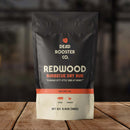 DDR BBQ Supply Dead Rooster Co Redwood barbecue dry rub in a black and cream pouch on a wooden surface