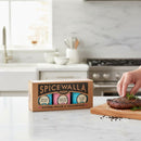 A hand seasons a steak with rosemary and finishing salt next to the Spicewalla Salt Collection 3 Pack by Spicewalla on a bright kitchen counter, with a stove and utensils in the background.