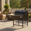 The Smokin Brothers “30” Premier Plus Pellet Grill, a black American-made grill on wheels, is placed on a sunny patio near a fire pit with cushioned seating and greenery in the background.