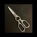 The Spaceman Knives Kitchen Shears by Spaceman Knives feature serrated stainless steel blades, large ergonomic handles, and a built-in bottle opener near the hinge—ideal for spatchcocking poultry and more on any dark surface.