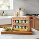 A hand holds the Spicewalla Signature Blends 10-Pack by Spicewalla on a kitchen counter. Nearby, a small bowl with lime wedges and cilantro sits on a wooden cutting board in a bright, modern kitchen.