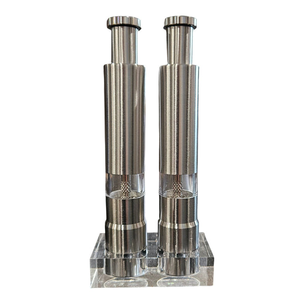 DDR BBQ Supply Thumb Grinders by DDR BBQ Supply feature two sleek stainless steel portable grinders with transparent midsections, standing upright on a clear acrylic base, isolated on a white background.