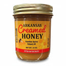 Guenther Apiary Arkansas Strawberry Creamed Honey is a 10 oz jar of raw, local honey with strawberry flavor, featuring a gold lid and yellow bee-and-honeycomb label from Guenther Apiary in Roland, AR.