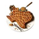 DDR BBQ Supply large Texas-shaped pecan cake topped with whole pecans on a white plate with vanilla beans and nuts.