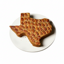 DDR BBQ Supply large Texas-shaped pecan cake topped with whole pecans on a white plate.