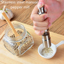 A hand seasons food one-handed with a DDR BBQ Supply Thumb Grinder, grinding pepper into a white dish. A glass peppercorn jar and wooden spoon rest nearby—essential DDR BBQ Supply accessories for any BBQ setup.