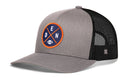 The Haka Hat Denver Trucker Hat | Black DEN X Football Snapback by Haka Hat is a stylish gray and black trucker hat featuring a breathable mesh back. The front displays a circular DEN X embroidered patch with the letters D, E, and N outlined in orange, along with a small white football graphic—making it the perfect snapback for football fans seeking both comfort and style.