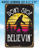 The Lone Star Art "Don't Stop Believing Big Foot" metal sign features a sunset background, Bigfoot silhouette, and bold text. Made of quality aluminum, it's 8x12—ideal for cabins or as a fun sasquatch gift.